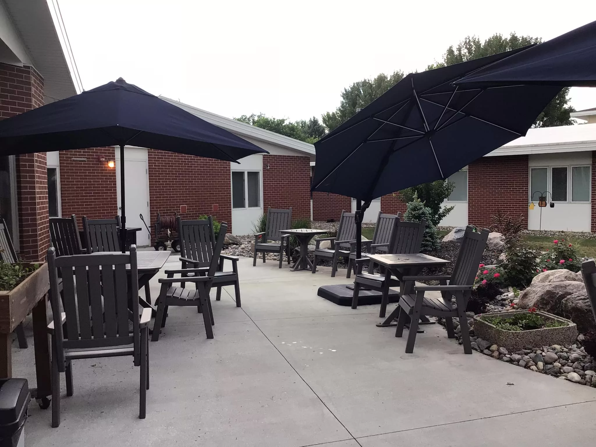 A cozy patio with outdoor seating, featuring tables and chairs under large umbrellas.