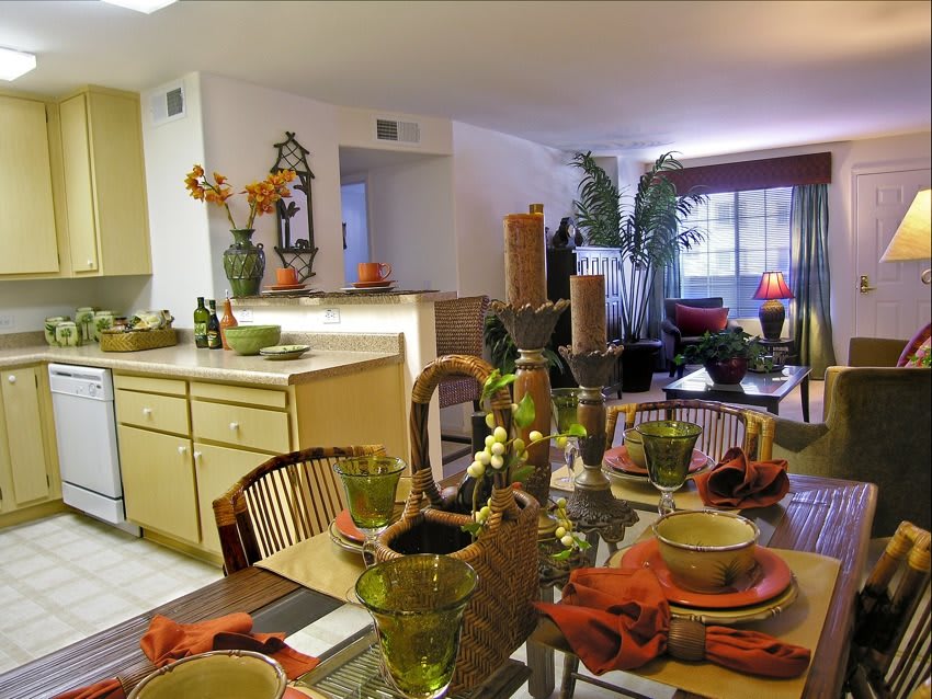 An open-concept home interior featuring a kitchen and dining area with a decorated table and plants.