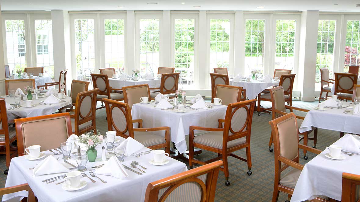 An elegant dining room with neatly arranged tables and chairs, set for a meal.