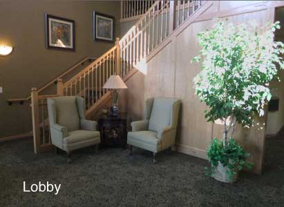 A cozy lobby area with two chairs, a side table, and a staircase backdrop.