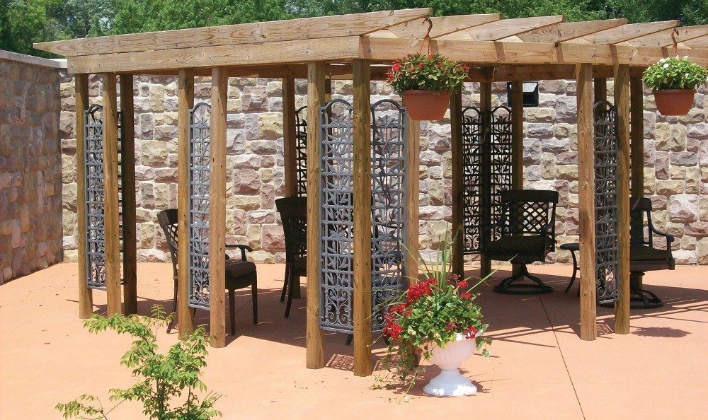 A cozy pergola with outdoor furniture and decorative planters in a garden setting.