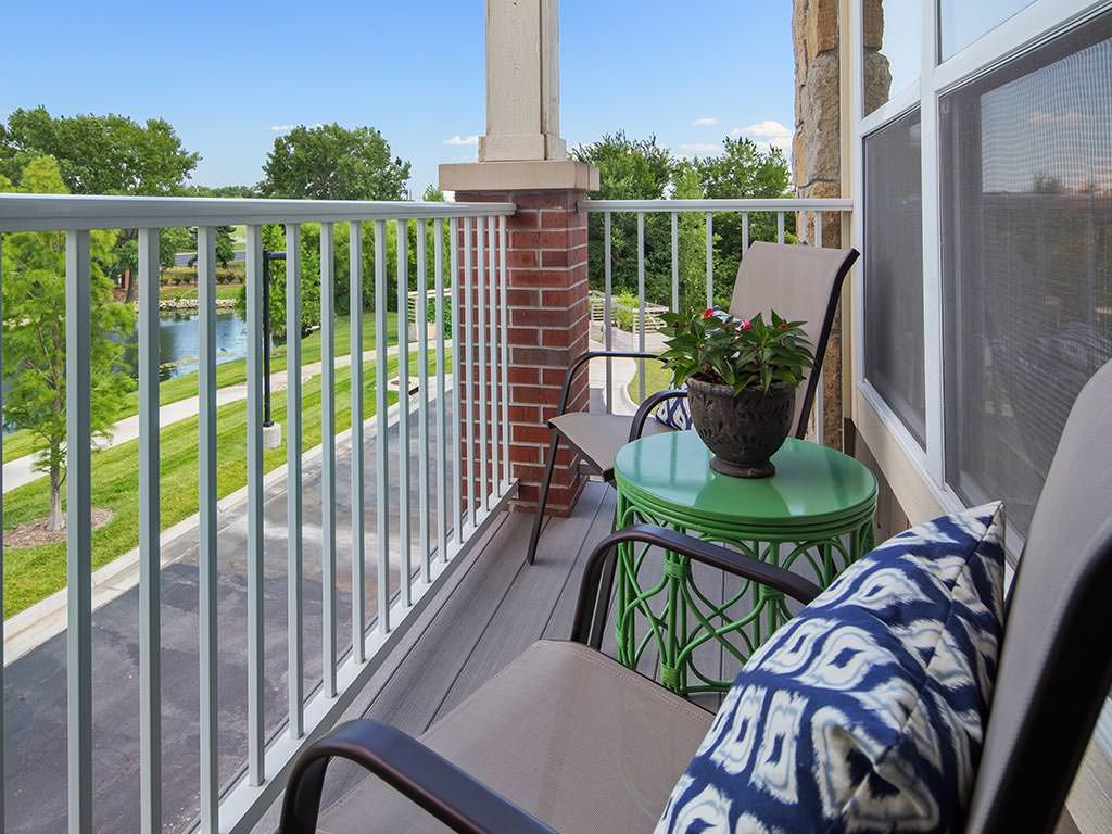 A cozy balcony with chairs and a table, overlooking a scenic area.