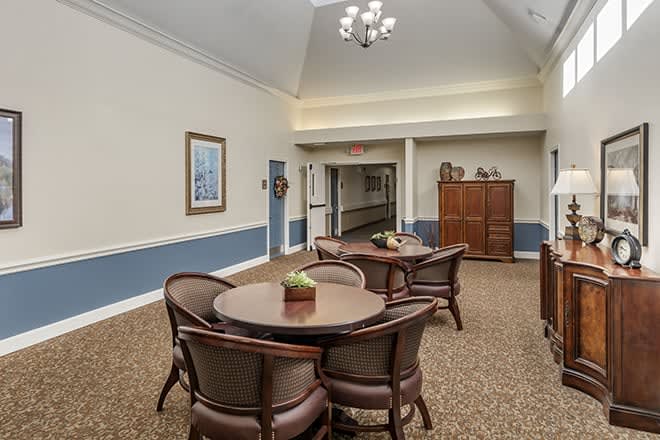 A cozy lounge area with tables and chairs, leading to a hallway.