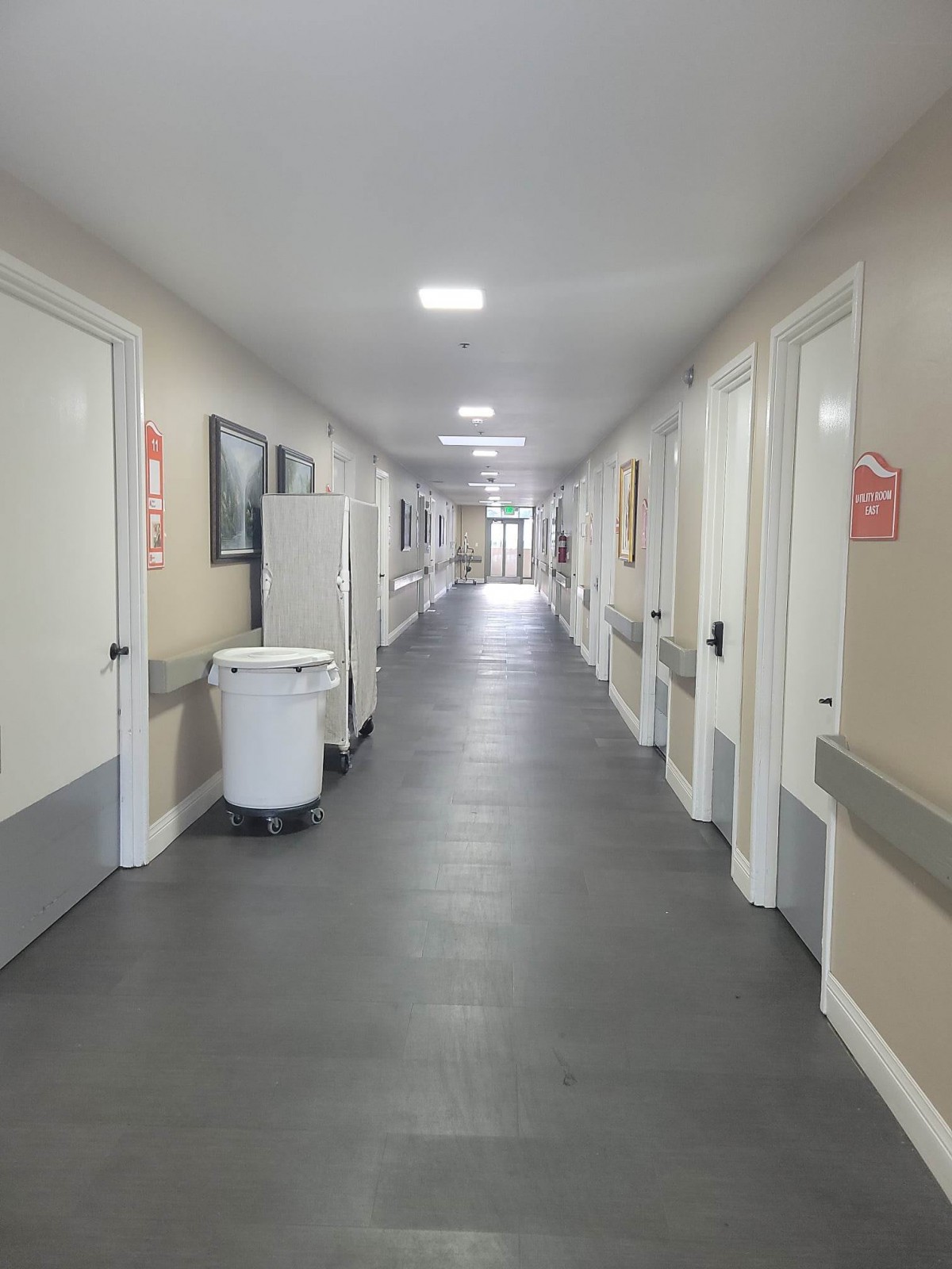 A clean and bright hospital corridor with several doors and medical equipment.