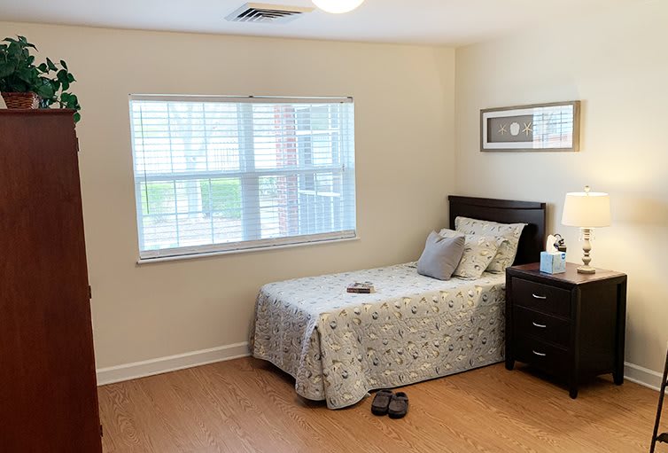 A cozy bedroom with a single bed and a nightstand, featuring minimalistic decor.