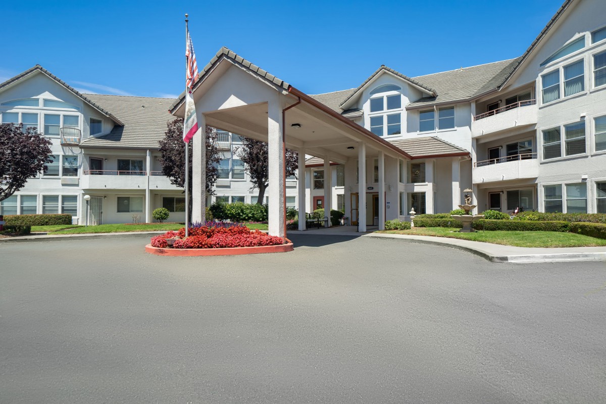 A well-maintained building entrance with landscaping and a flagpole.