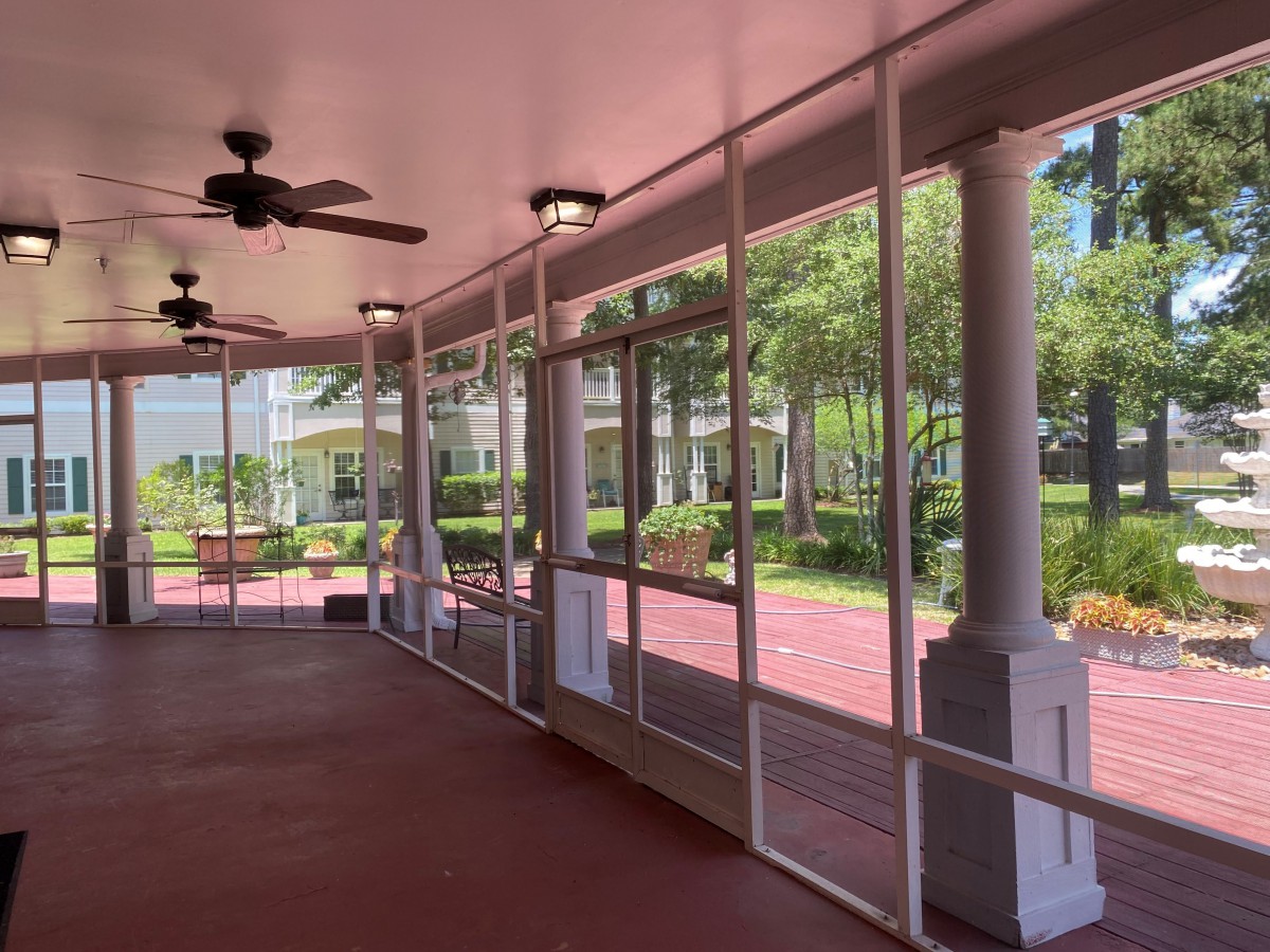 A spacious screened porch with ceiling fans and a view of the garden.