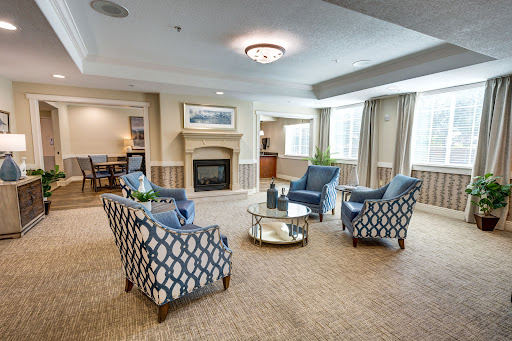 A cozy and modern living room setup featuring stylish blue upholstered chairs and a central coffee table, illuminated by natural light.