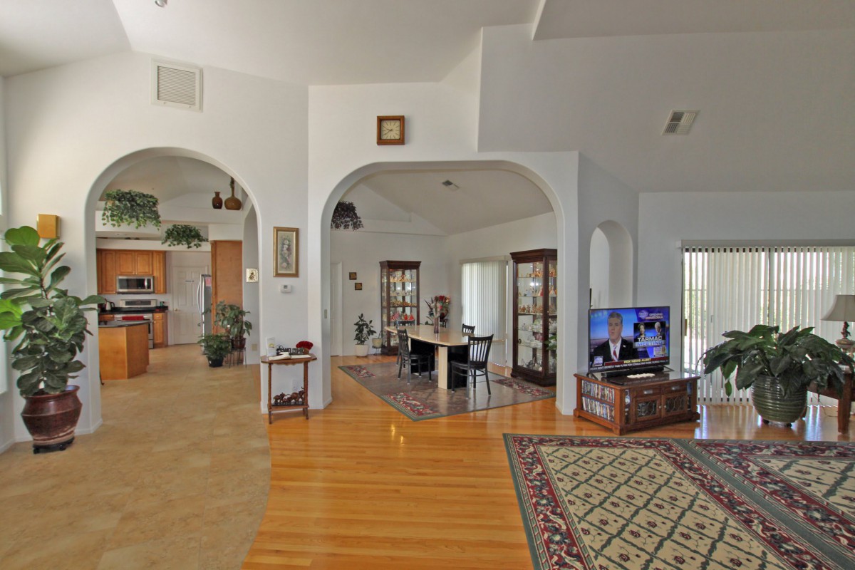 A spacious living room with an open floor plan, featuring archways and hardwood floors.