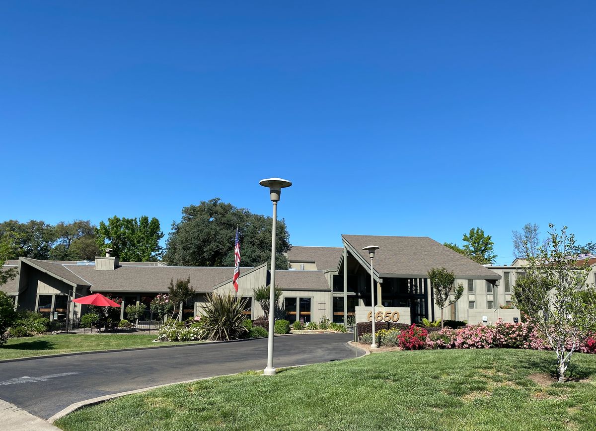 A modern building with a well-maintained lawn under a clear blue sky.