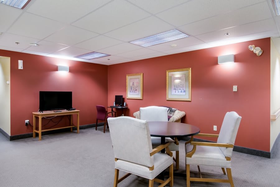 A comfortable lounge area with chairs, a table, a television, and computer station.