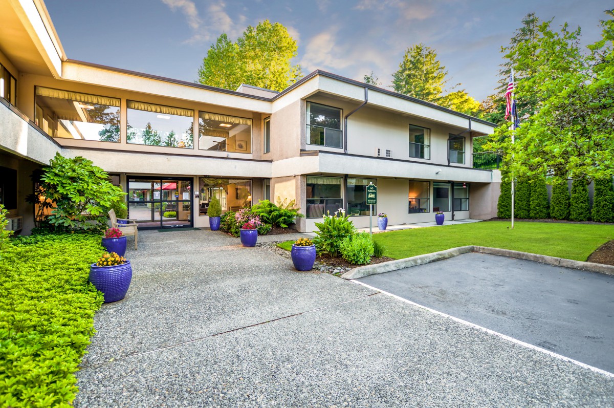 A modern two-story house with large windows, a well-maintained garden, and a spacious driveway.