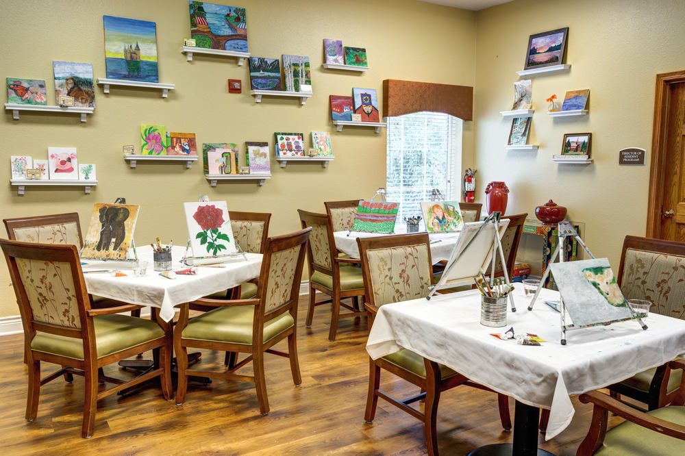 A cozy art studio with paintings displayed on the walls and tables set up for painting activities.