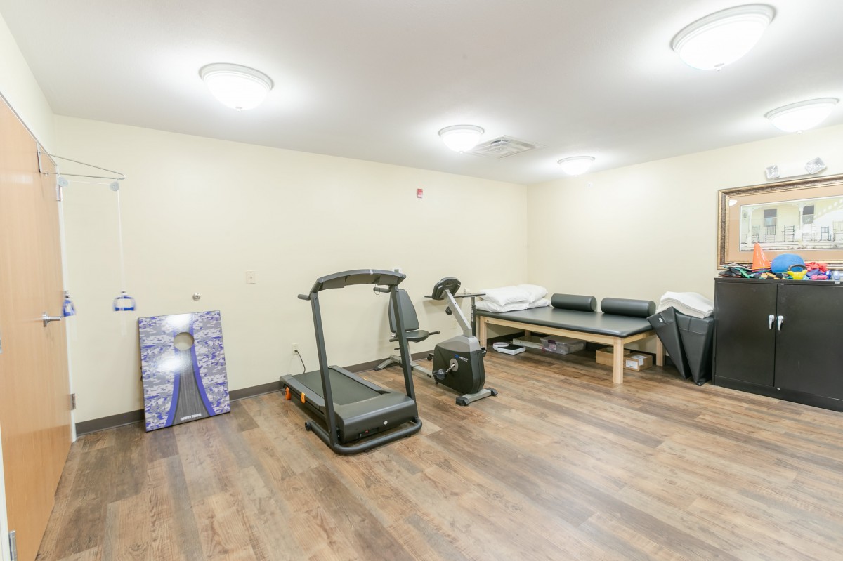 A small exercise room with a treadmill and other fitness equipment.