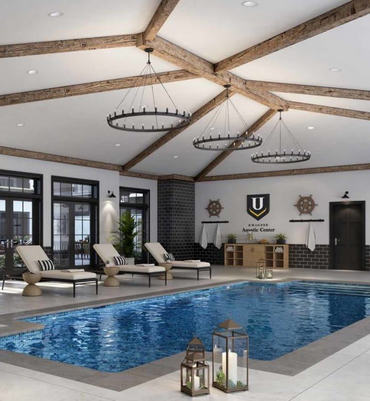 A luxurious indoor pool area featuring modern chandeliers and comfortable lounge chairs.
