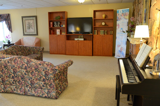 A cozy living room setup featuring a television, bookshelves, comfortable seating, and a piano.