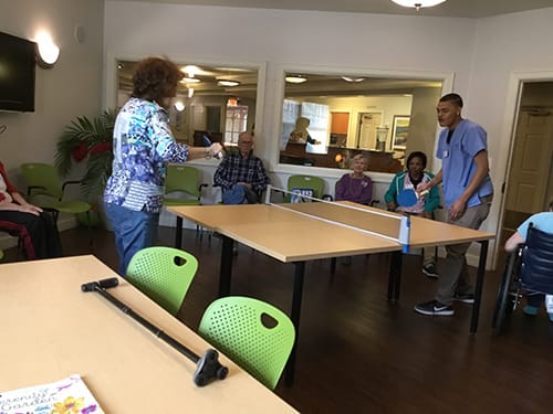 A group of adults participating in an indoor table tennis activity.