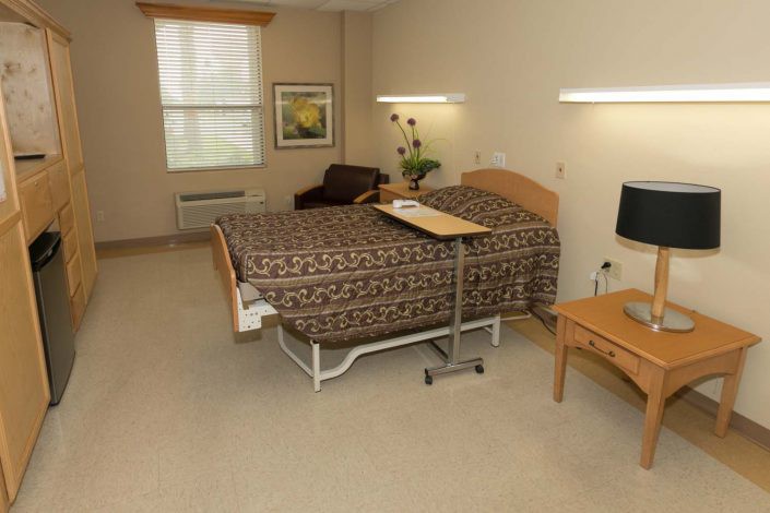 A clean and organized hospital room with a bed and essential furniture.