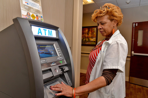 A person interacting with an ATM to withdraw cash.