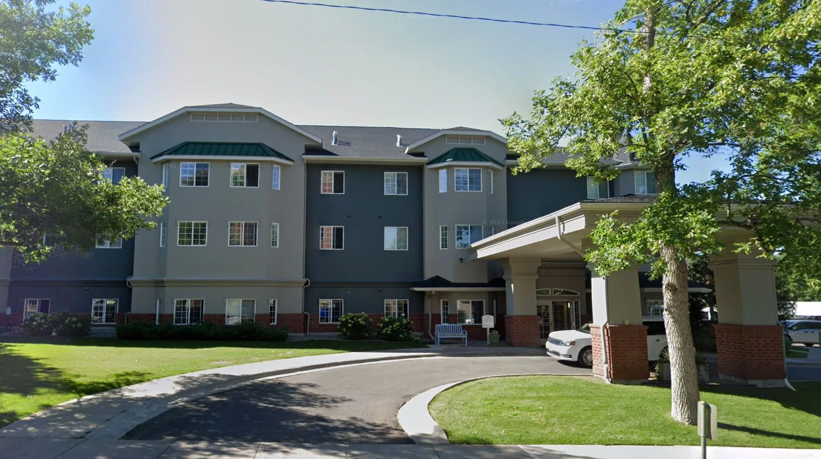 A multi-story residential building with a driveway and landscaped surroundings.
