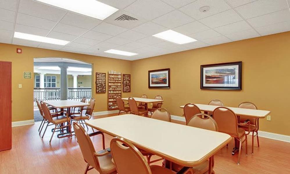 A community dining area with tables and chairs, featuring warm lighting and decorated walls.