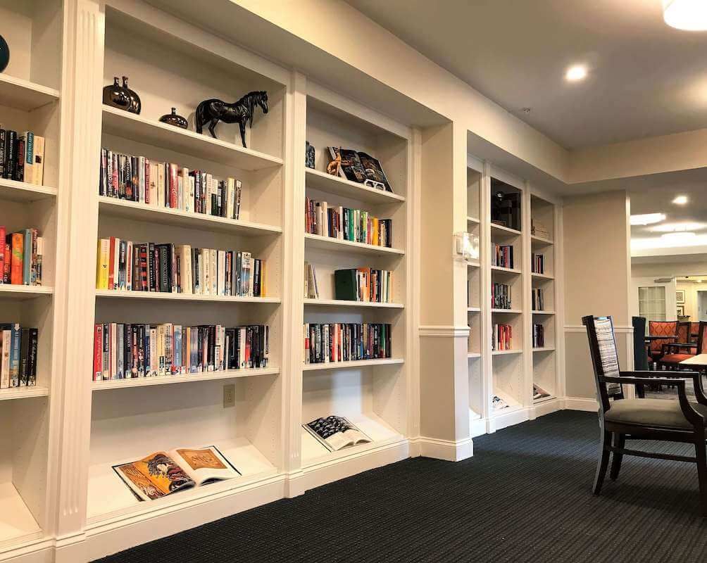 A cozy library with bookshelves filled with various books and comfortable seating arrangements.