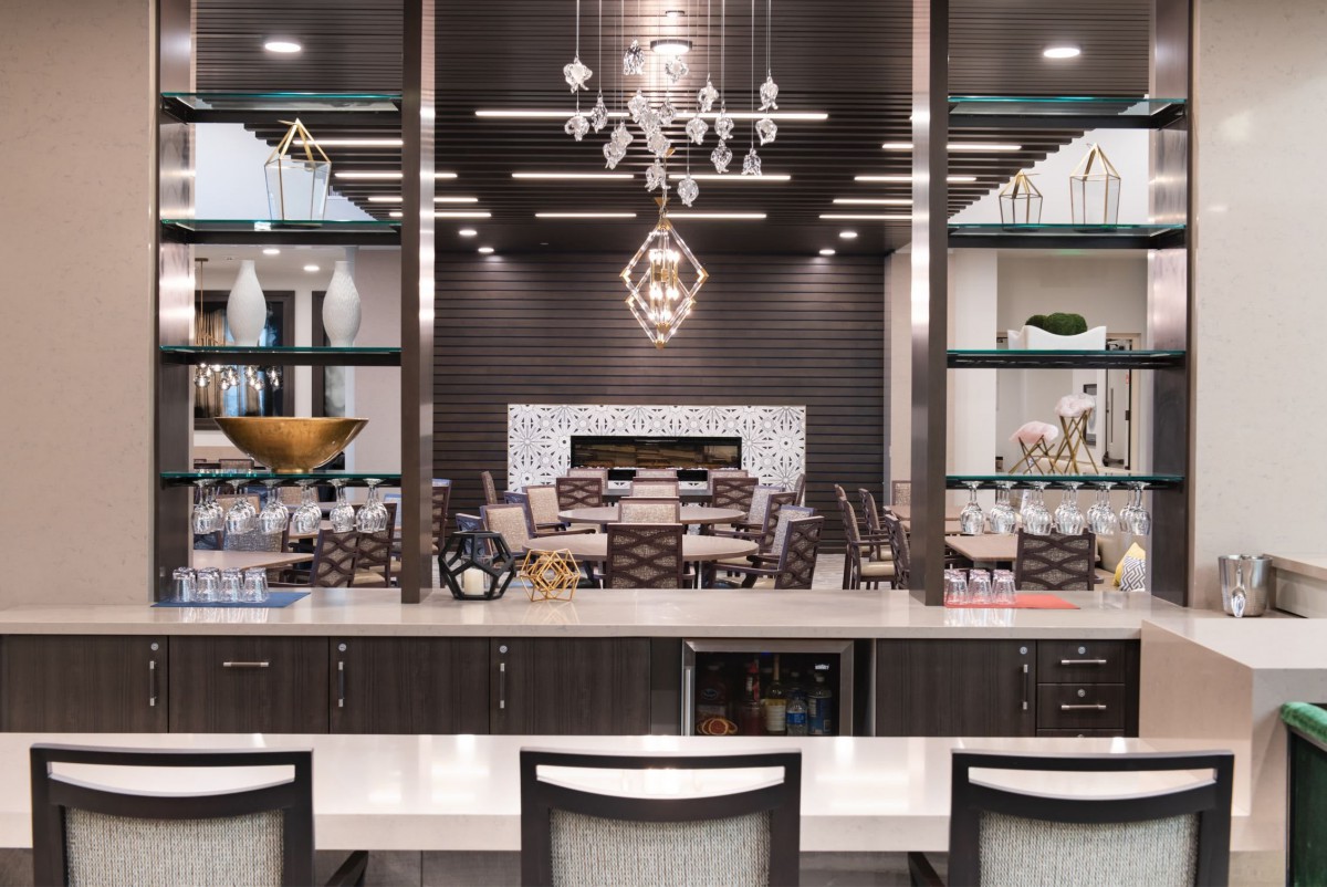 A modern kitchen and bar area with elegant chandeliers, sleek shelves, and stylish decor.