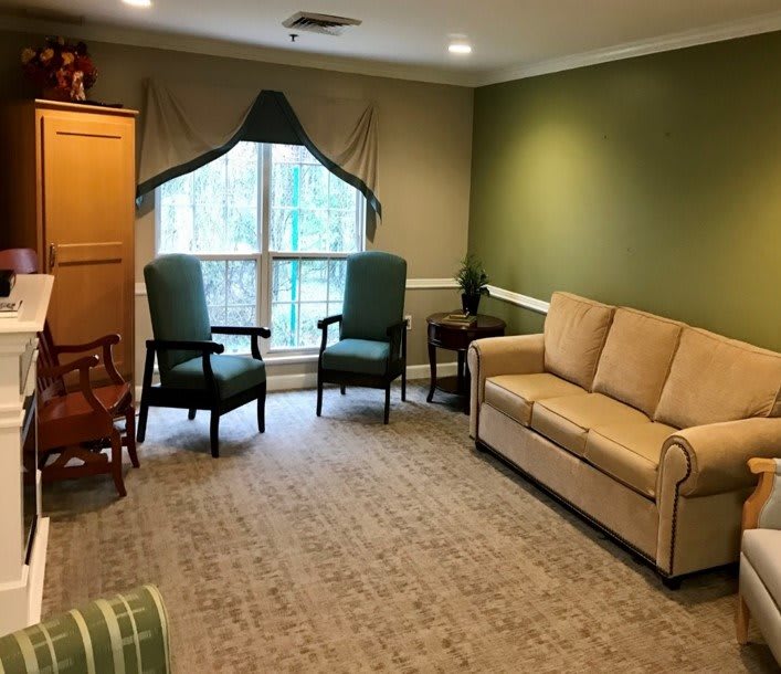 A cozy living room with a sofa, two chairs, and natural light coming through the window.