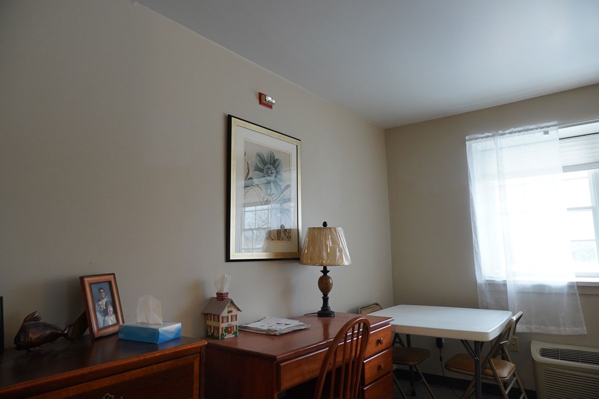 A cozy room with a wooden desk and lamp next to a window.
