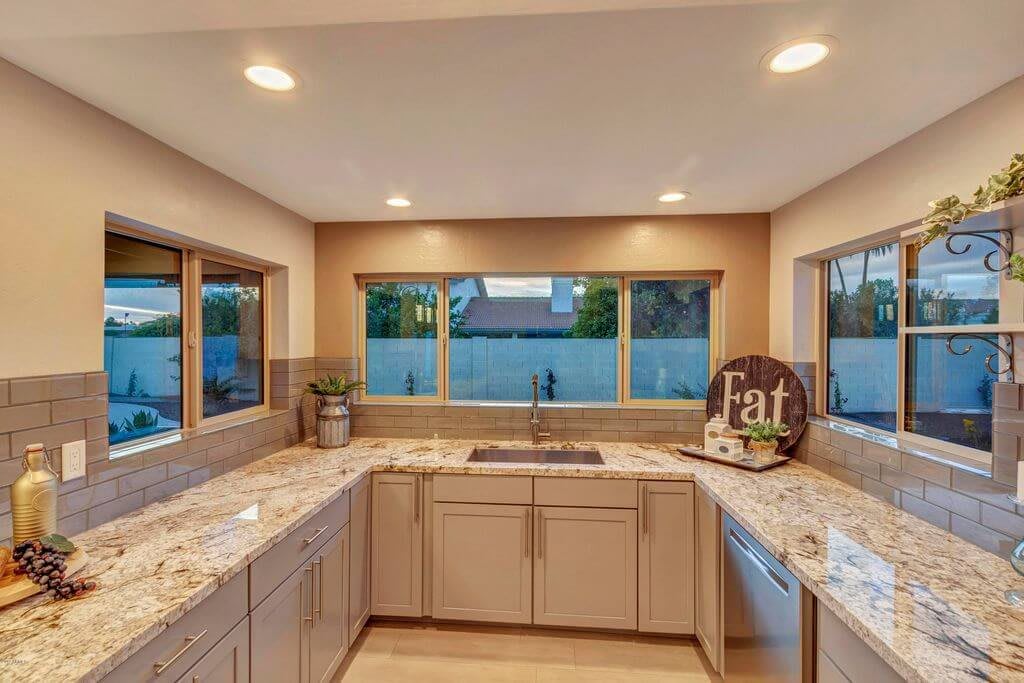 A modern kitchen with spacious countertops and ample natural light from large windows.