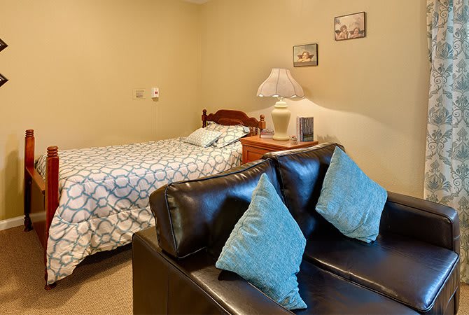 Cozy bedroom with a double bed, sofa, and bedside lamp.