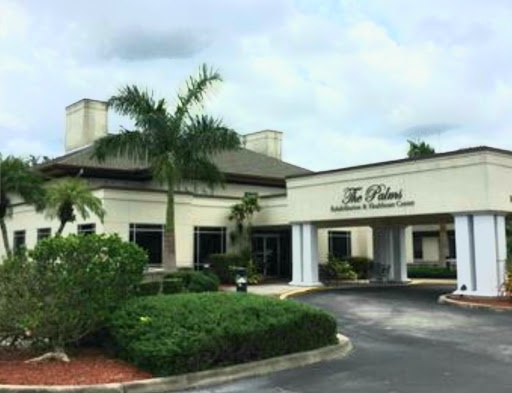 The exterior view of a commercial building featuring lush landscaping and palm trees.