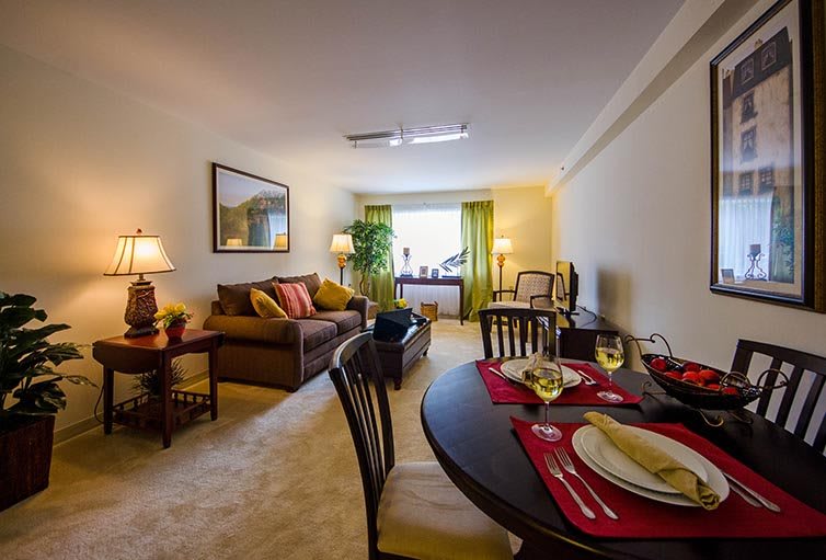 A cozy living room and dining area with elegant decor, featuring a comfortable sofa and a table set for two.