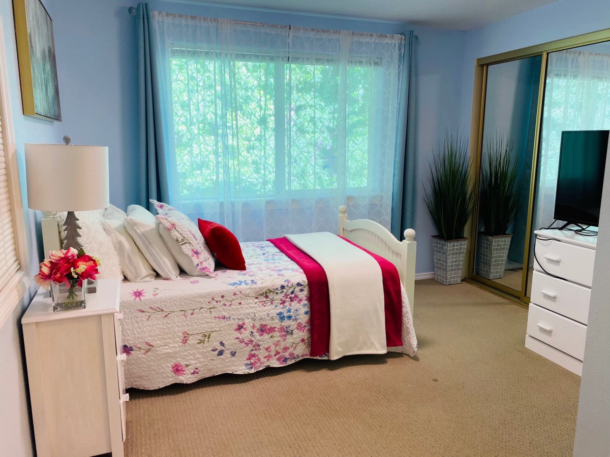 A cozy bedroom with floral bedding and a large mirror.