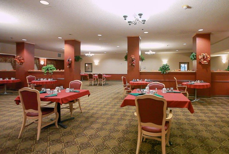An elegant dining area with tables dressed in red tablecloths and neatly arranged place settings.