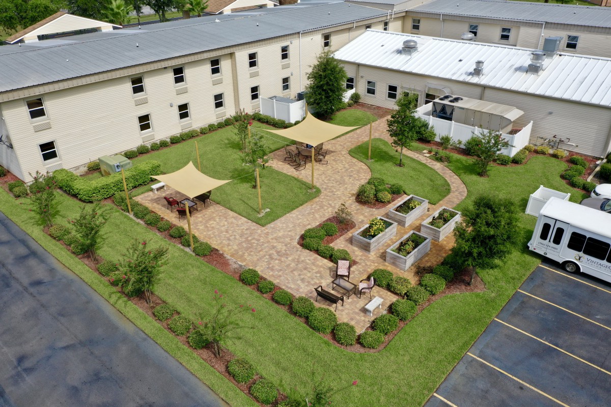 Aerial view of a landscaped courtyard with walkways, benches, and greenery surrounded by buildings.