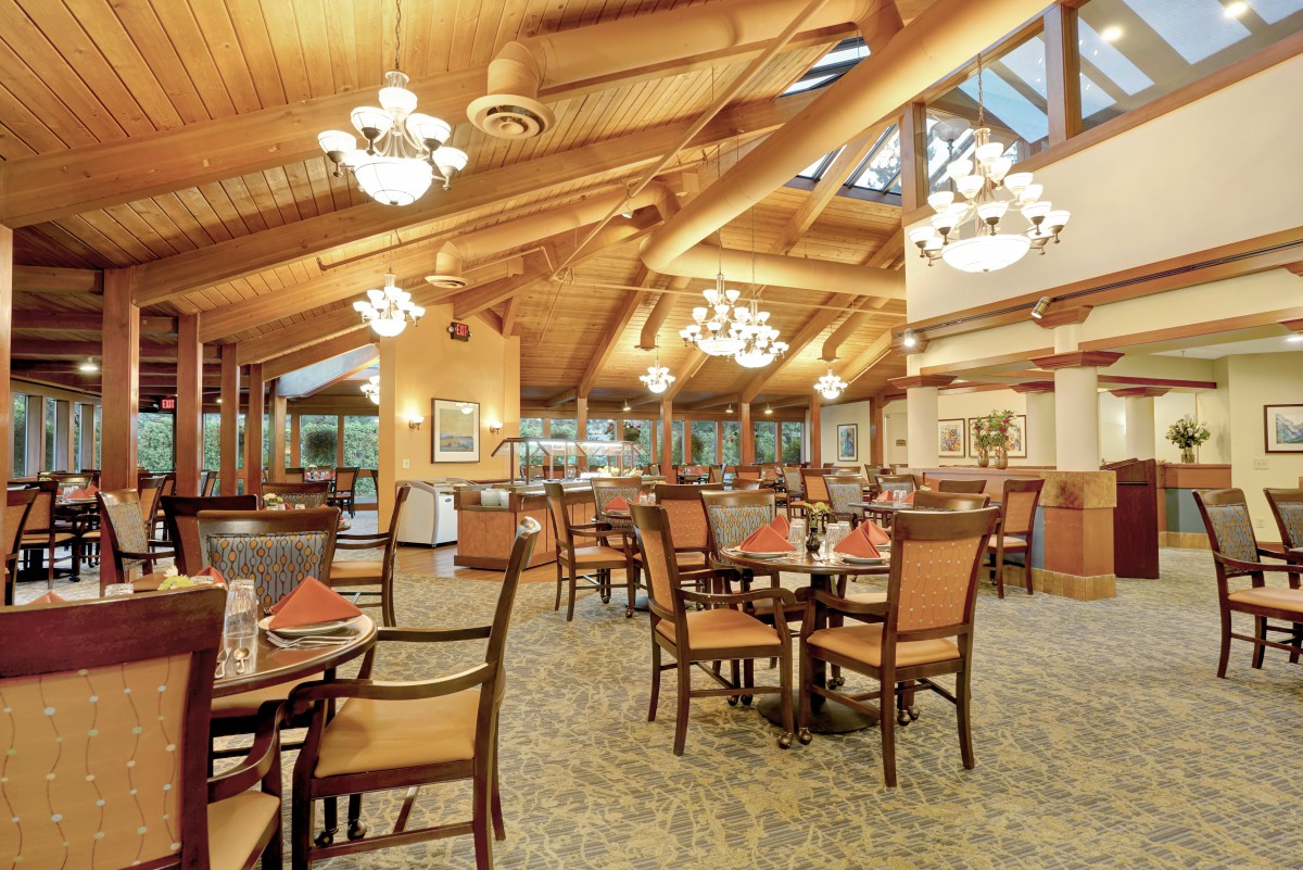 A cozy restaurant interior with wooden ceilings and elegant chandeliers.