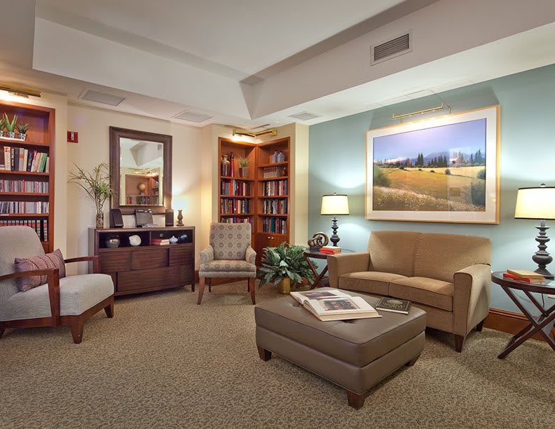 A cozy living room with comfortable seating, a bookshelf, and warm lighting.