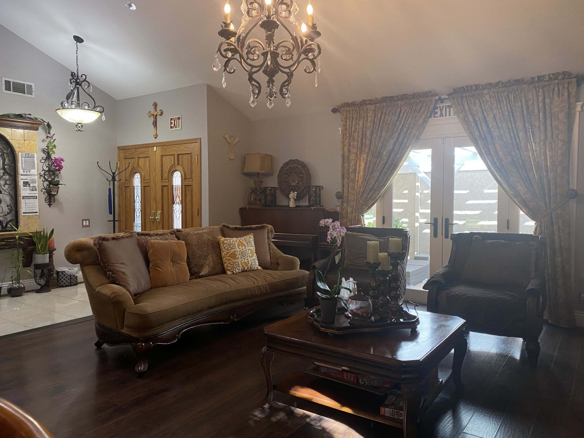 A traditional living room featuring elegant chandeliers, classic sofas, and rich wooden furnishings.