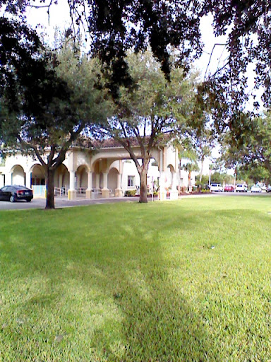 A serene outdoor space featuring a building surrounded by lush greenery and trees.