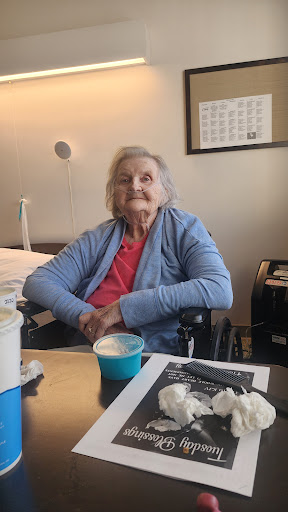 An elderly woman sitting comfortably in her wheelchair, enjoying a moment indoors with a smile.