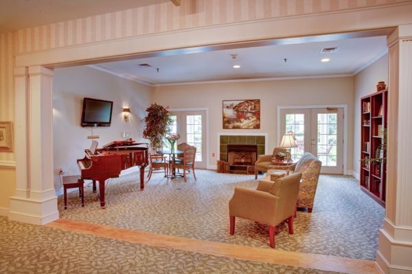 A cozy living room with a piano, seating area, and fireplace.