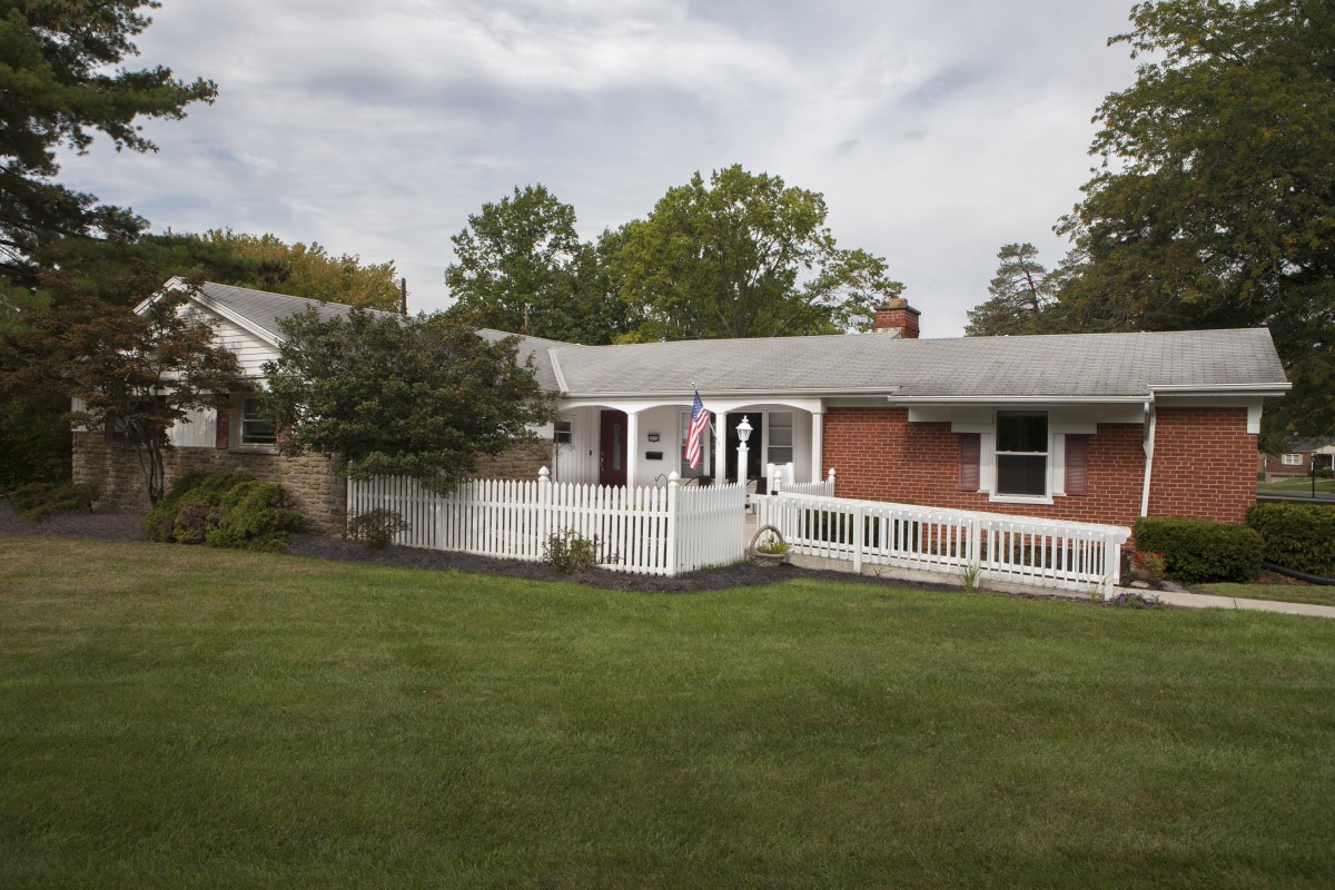 A suburban house with a spacious front lawn and surrounding trees.