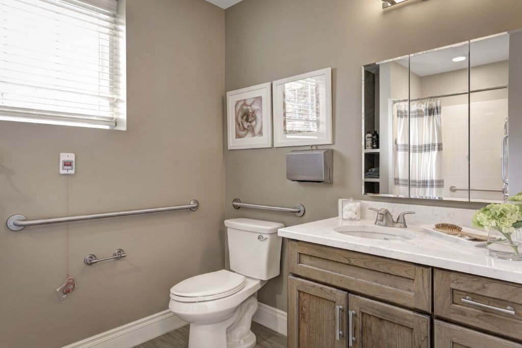 A modern bathroom with a toilet, sink, mirror, and decorative wall art.