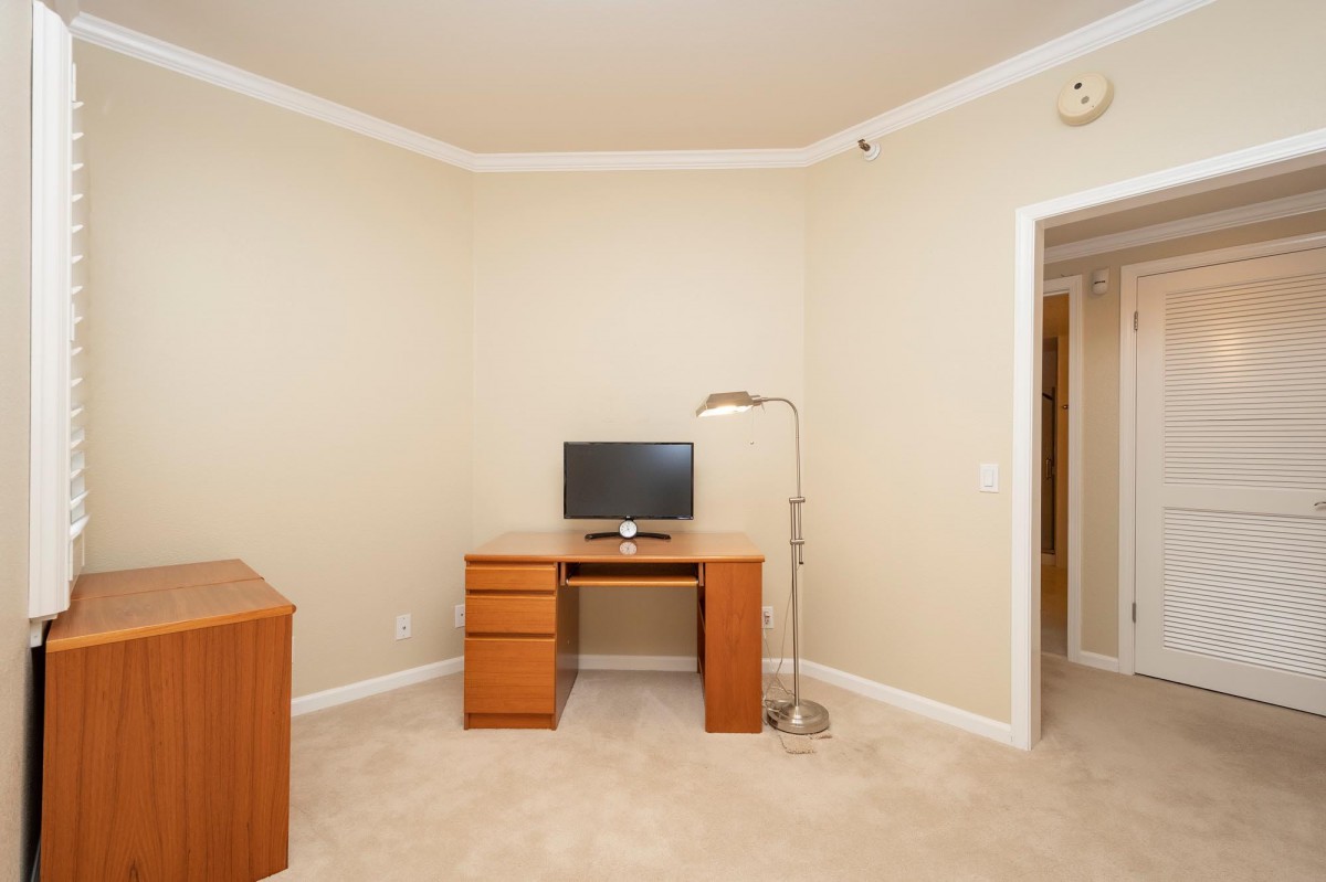 A minimalist office space with a desk, computer, and lamp.