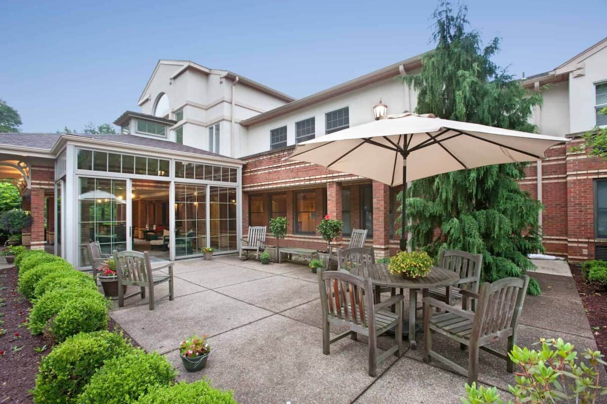 A cozy patio area with outdoor seating and an umbrella, set against a modern building exterior.