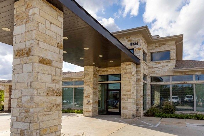 Modern building with a stone facade and large glass windows.