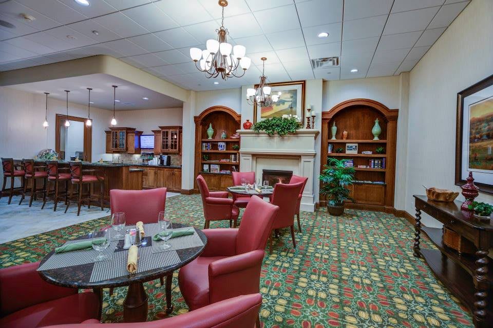 A cozy lounge area with elegant chandeliers, plush seating, and bookshelves creating a warm atmosphere.