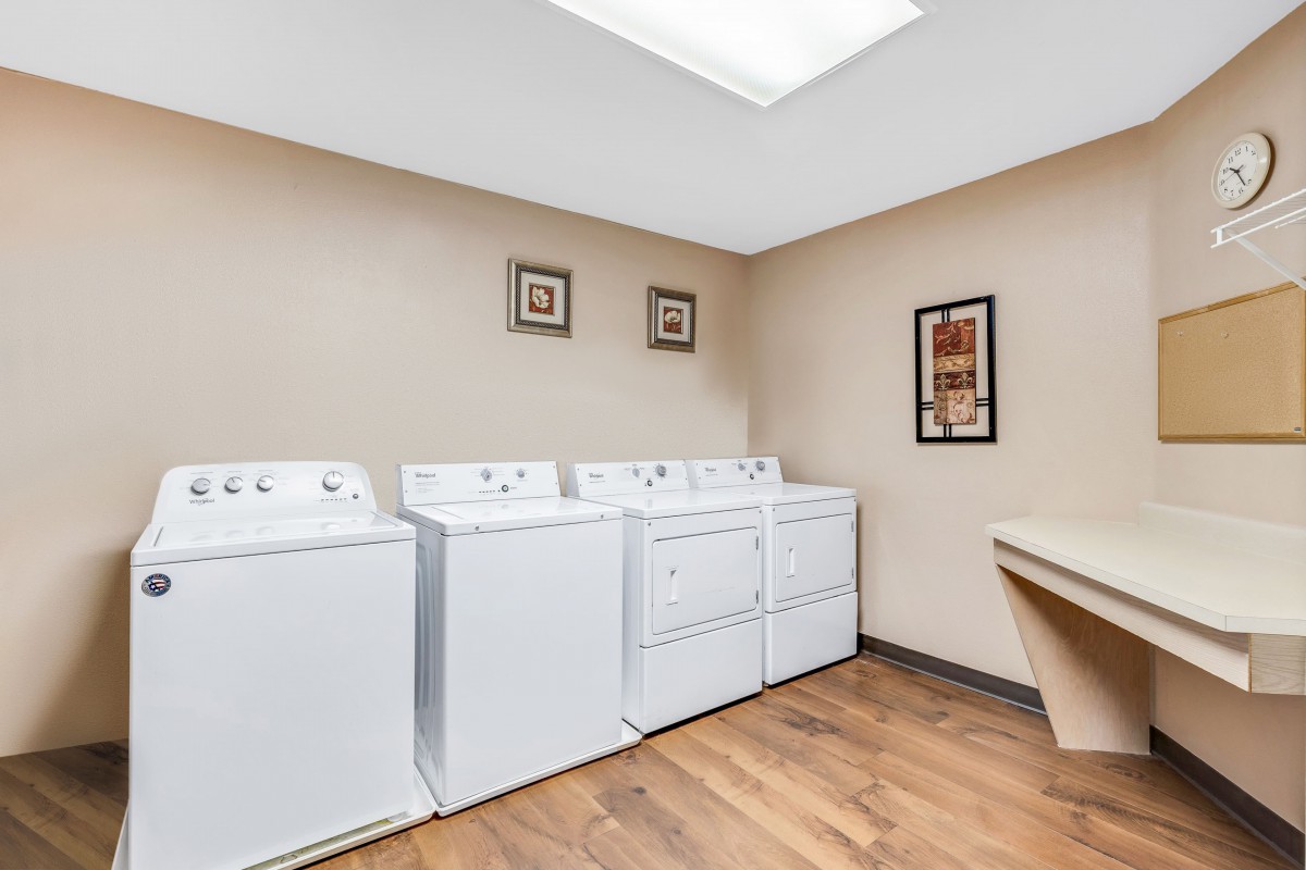 A tidy laundry room with washing machines and a dryer lined up against the wall.
