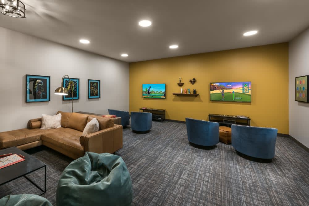 A modern living room with comfortable seating and wall-mounted televisions.